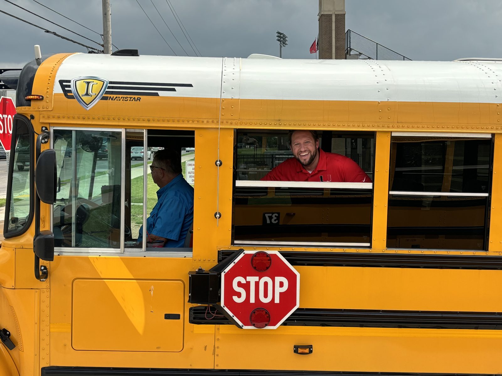 John Watkins smiling out of a Union Public Schools bus window in his red school polo